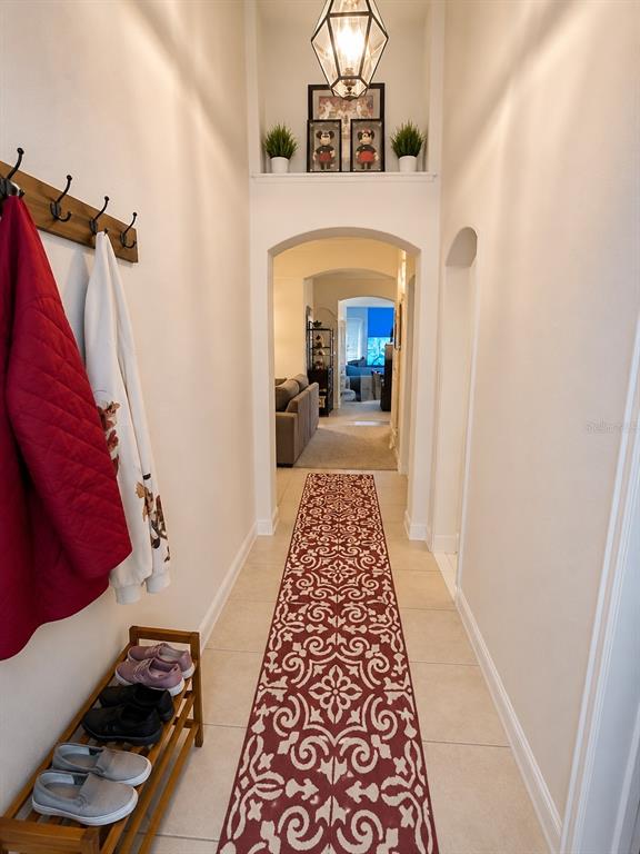 A hallway features a patterned red runner, a shoe rack, and an arched entryway — 733 SADDLE RIDGE DRIVE, DAVENPORT, FL