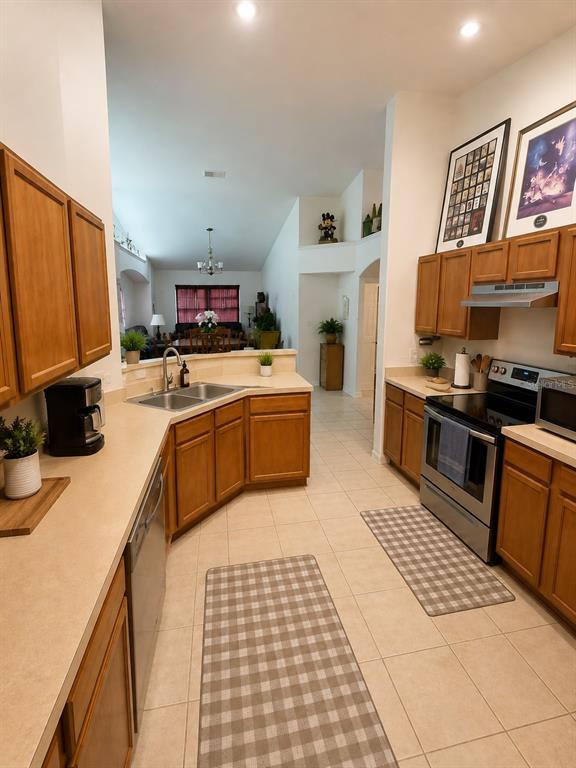 A kitchen with wood cabinets, light countertops, and tile flooring opens to a dining area — 733 SADDLE RIDGE DRIVE, DAVENPORT, FL