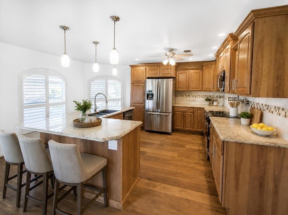 A kitchen with wood cabinets, granite countertops, stainless steel appliances, and a breakfast bar island — 1343 UNDERHILL CIRCLE, PORT CHARLOTTE, FL