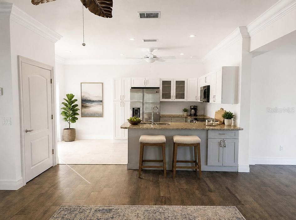 A kitchen with white upper cabinets, gray lower cabinets, a granite island, and wood flooring — 1343 UNDERHILL CIRCLE, PORT CHARLOTTE, FL