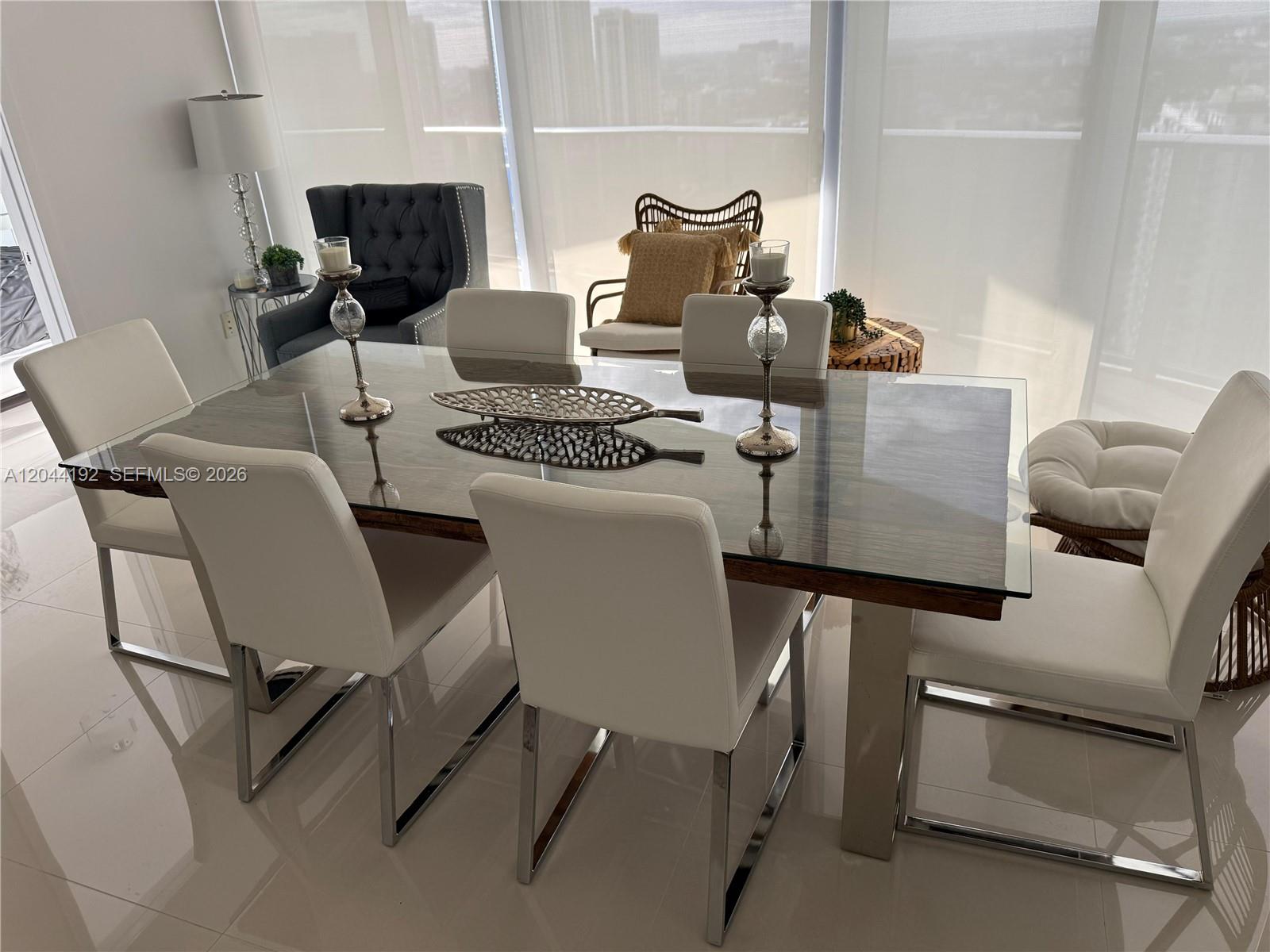 A dining room features a glass-topped table, white chairs, and large windows with city views — 488 NE 18th St # 2701, Miami FL 33132, MIAMI, FL