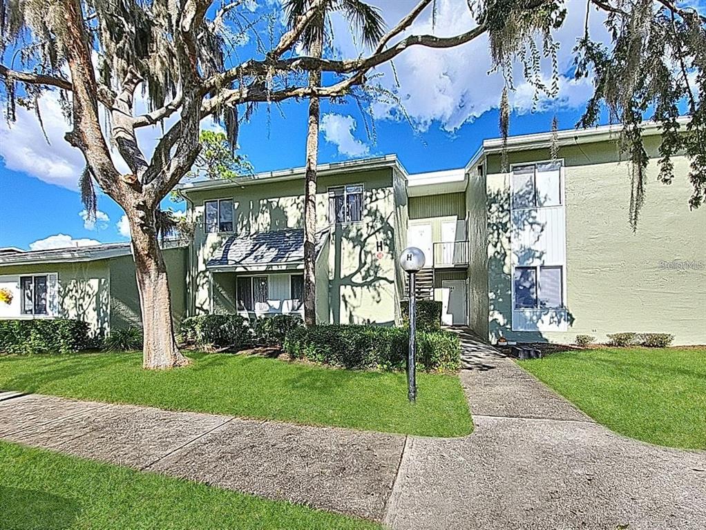 A two-story apartment building with light green stucco walls and a grassy front lawn — 568 FAIRWAYS CIRCLE UNIT A, OCALA, FL