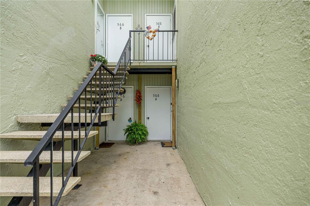 An exterior view of a two-story building with a concrete staircase leading to upper units — 568 FAIRWAYS CIRCLE UNIT A, OCALA, FL