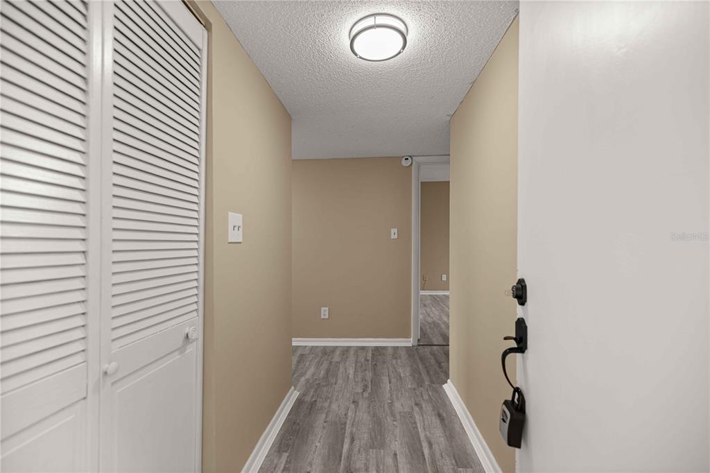 A hallway with light-colored walls, wood-look flooring, and a white louvered closet door — 568 FAIRWAYS CIRCLE UNIT A, OCALA, FL