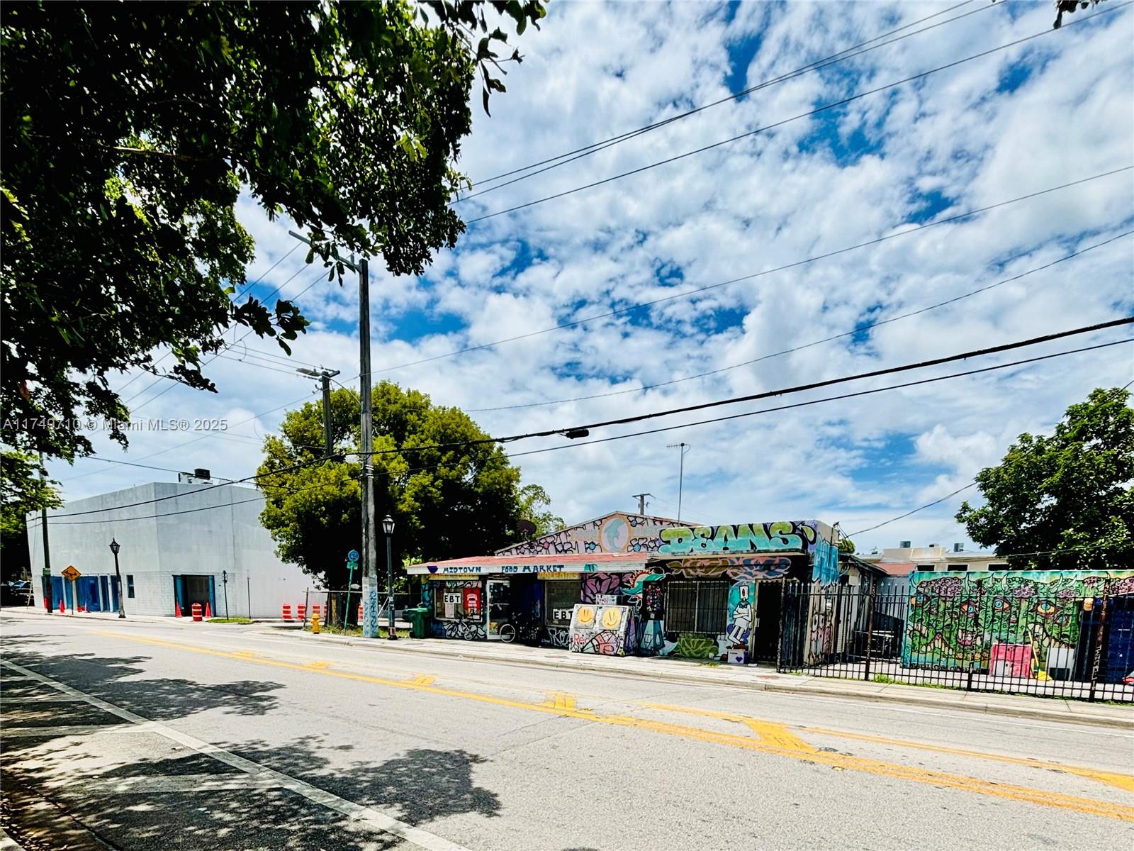 A street-level view of a graffiti-covered food market building under a cloudy blue sky — 203 NW 35th St, Miami FL 33127, MIAMI, FL