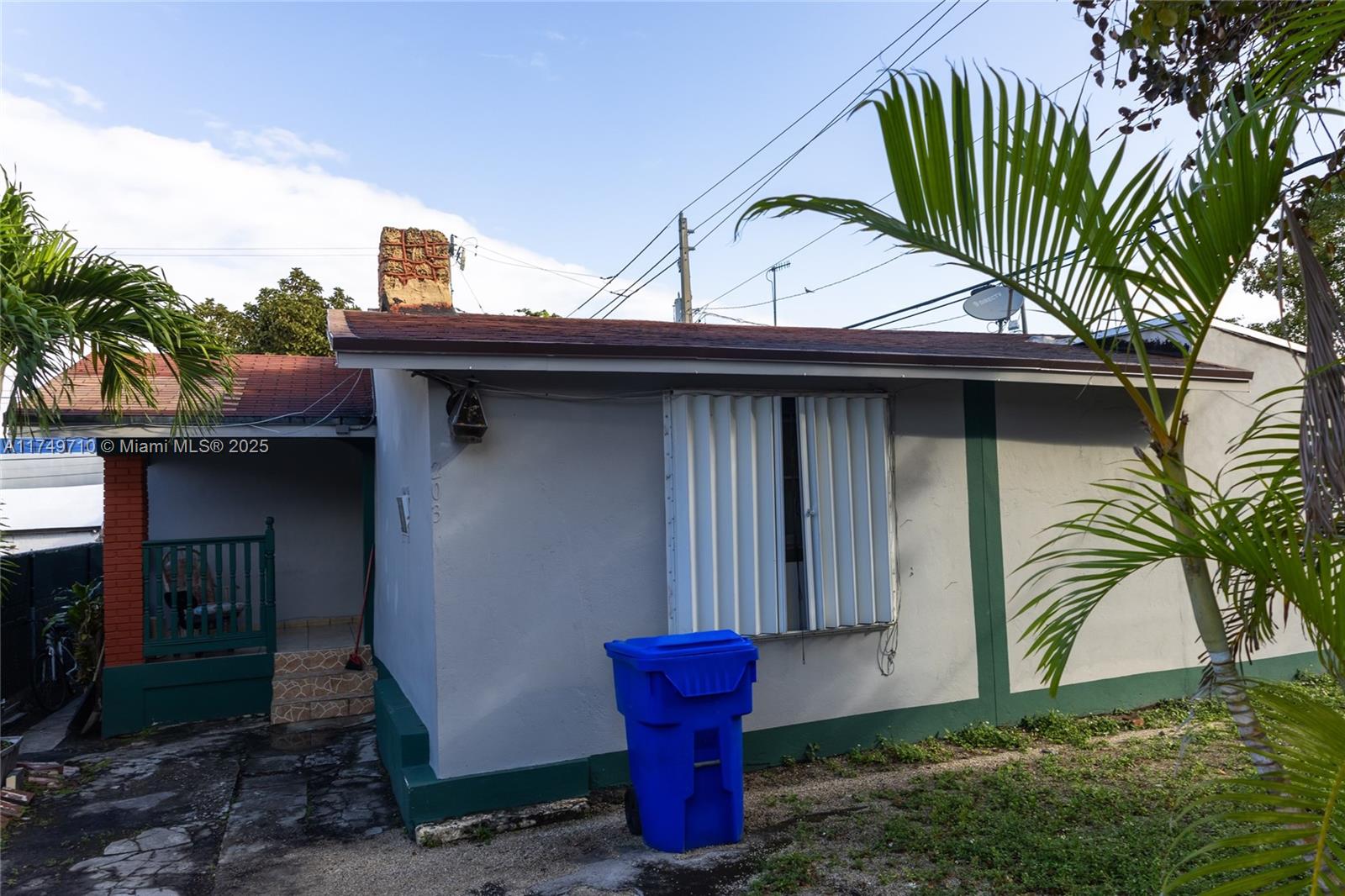The exterior of a single-story house features a chimney, a window with shutters, and a trash bin — 203 NW 35th St, Miami FL 33127, MIAMI, FL