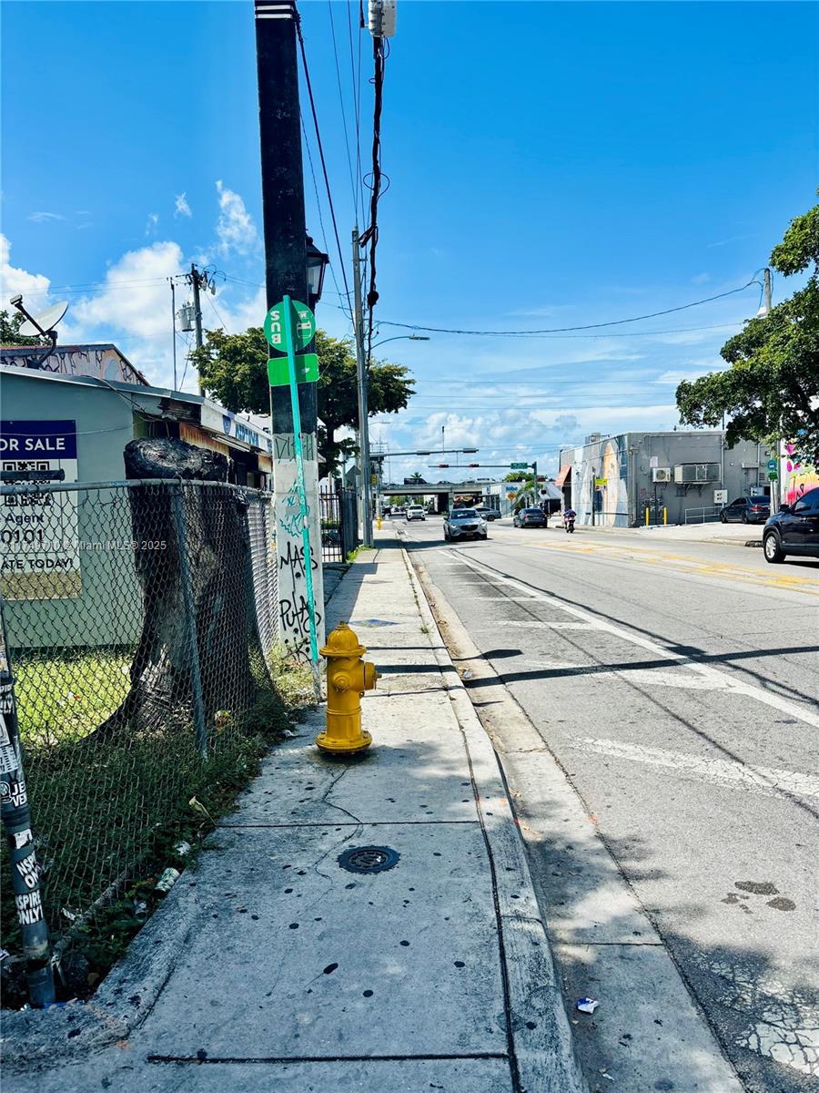 A sidewalk runs alongside a road with a yellow fire hydrant and a bus stop sign — 203 NW 35th St, Miami FL 33127, MIAMI, FL