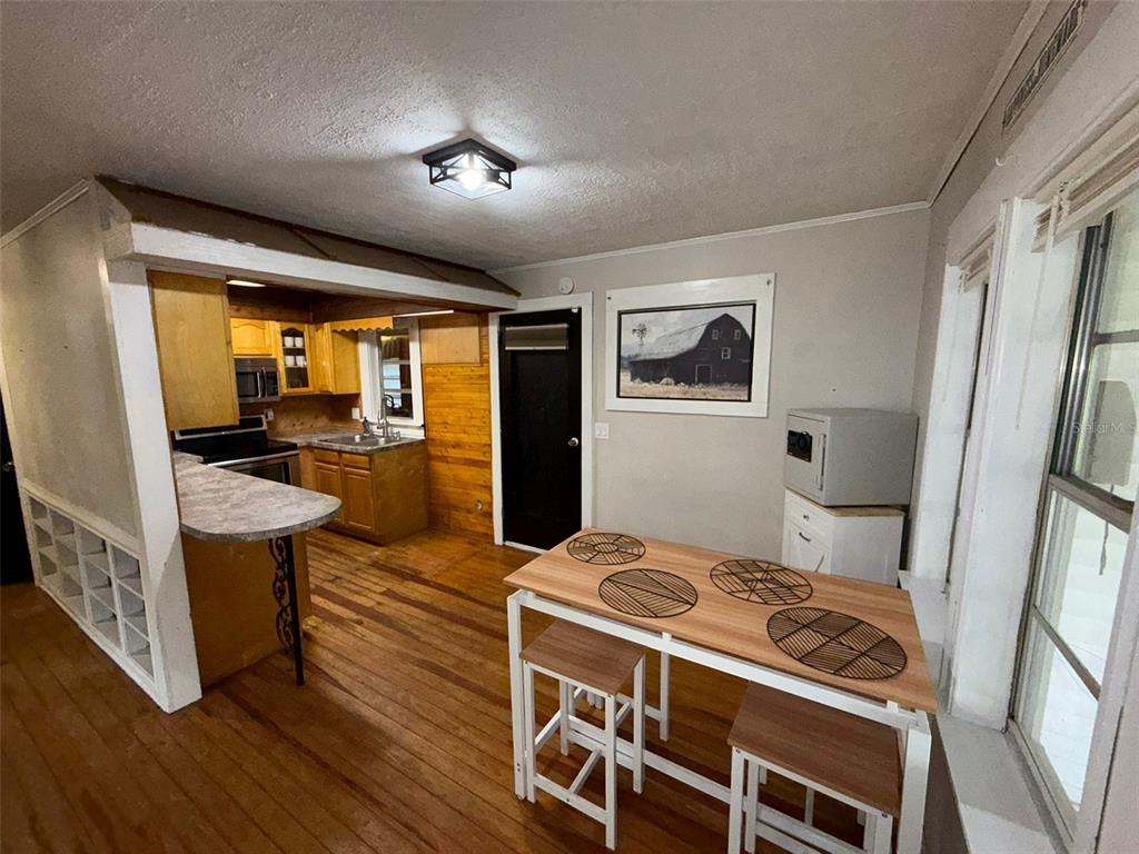 A kitchen and dining area with wood flooring, a breakfast bar, and a small table — 37318 CARTER AVENUE, DADE CITY, FL