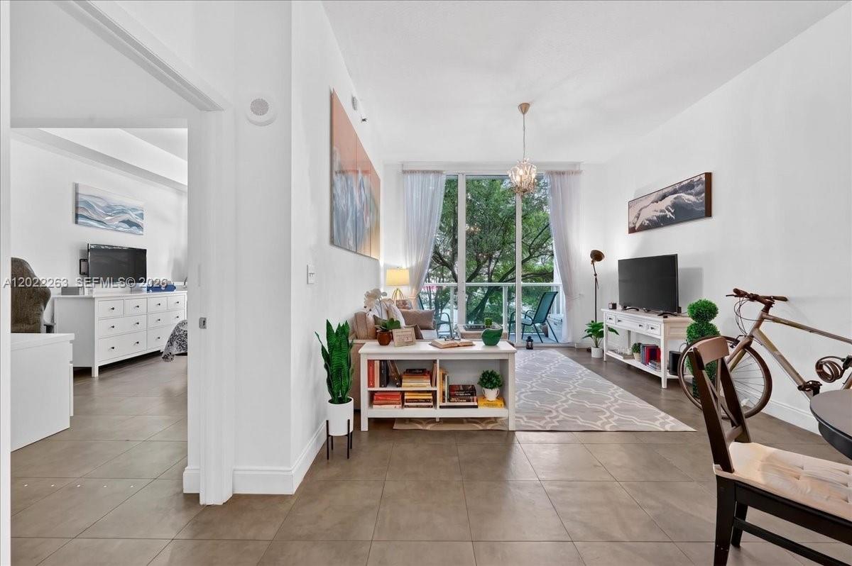 A living room features tile floors, a white media console, and a balcony with trees — 31 SE 5th St # 203, Miami FL 33131, MIAMI, FL