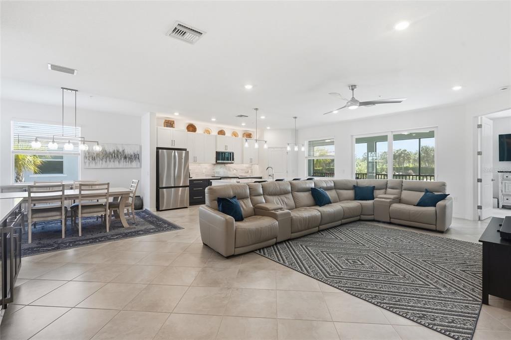 An open-concept living room and kitchen featuring tile flooring, a large sectional, and dining area — 14842 BIRCHWOOD COURT UNIT 6521, PUNTA GORDA, FL