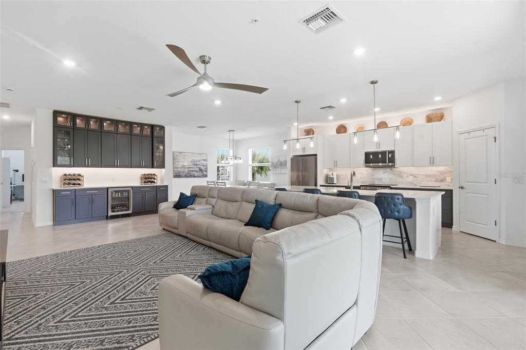 An open-concept living room and kitchen featuring a large sectional sofa and dark cabinetry — 14842 BIRCHWOOD COURT UNIT 6521, PUNTA GORDA, FL
