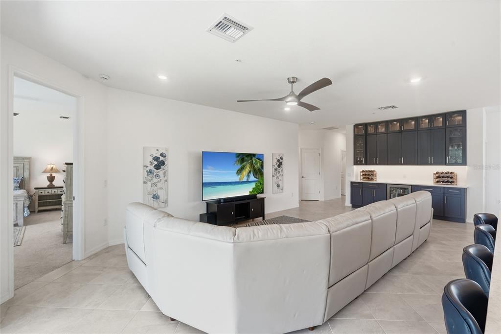 A living room features a large white sectional sofa, a television, and dark blue cabinetry — 14842 BIRCHWOOD COURT UNIT 6521, PUNTA GORDA, FL