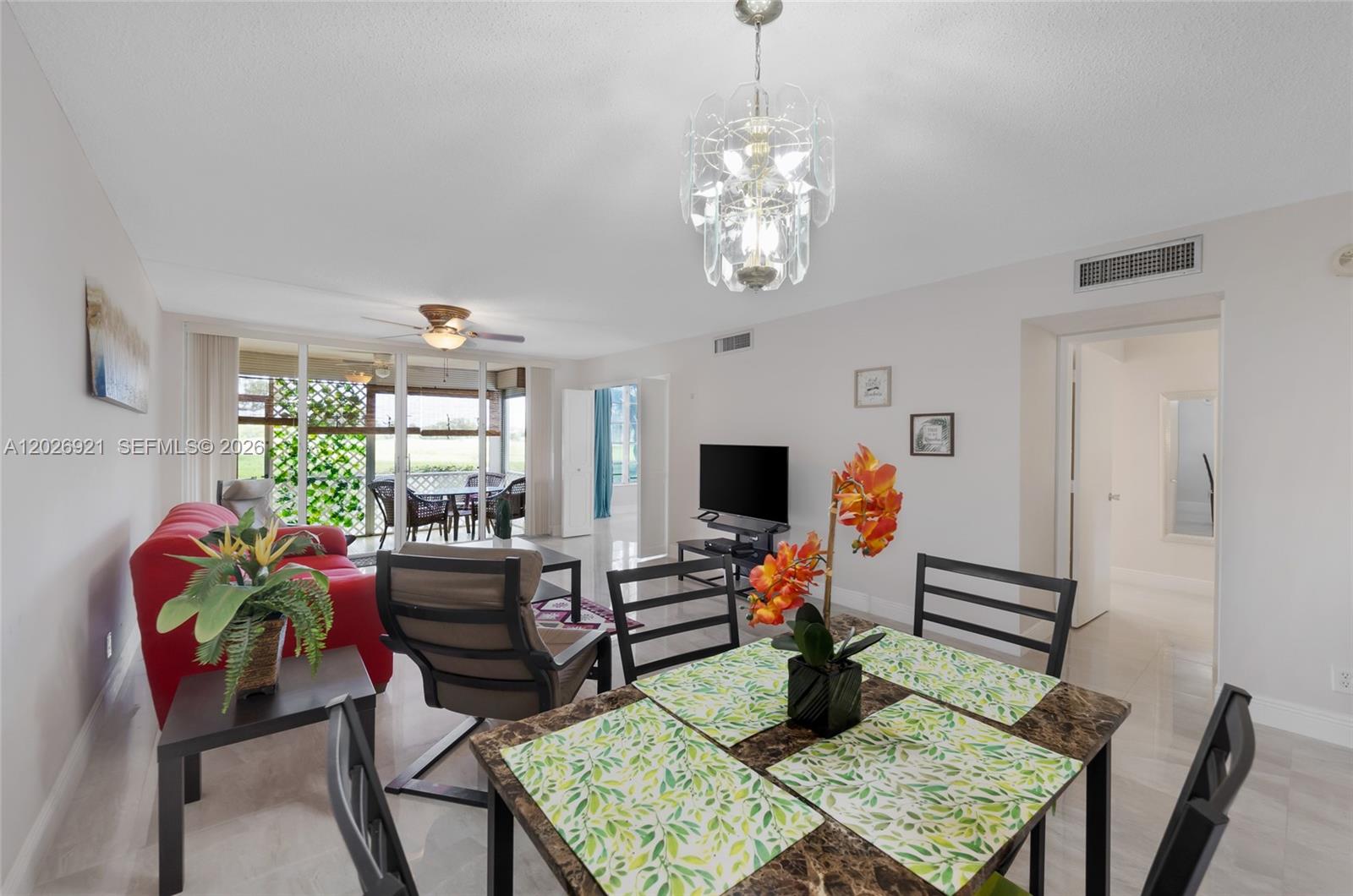A dining area with a marble-topped table opens into a living room with a red sofa — POMPANO BEACH, FL