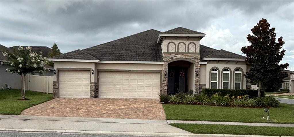 A single-story house with a stone facade, arched windows, and a paved driveway — 2504 CAVENDER CREEK ROAD, MINNEOLA, FL