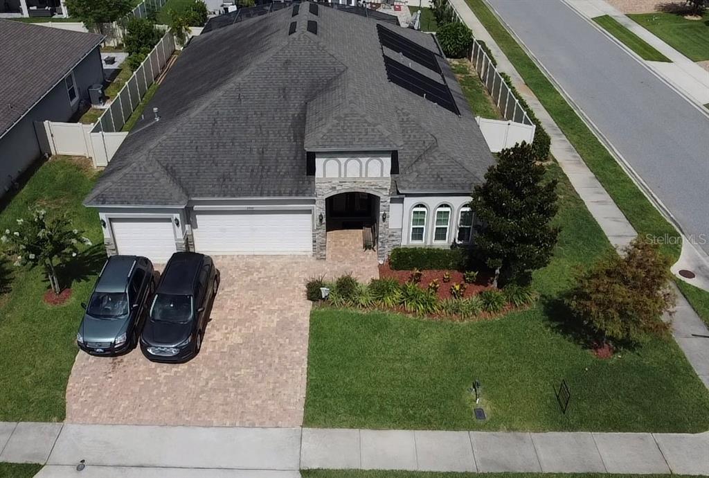An aerial view shows a single-story house with a paver driveway and solar panels — 2504 CAVENDER CREEK ROAD, MINNEOLA, FL