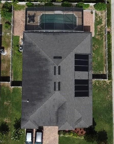 An aerial view shows a house with a screened pool and solar panels on the roof — 2504 CAVENDER CREEK ROAD, MINNEOLA, FL