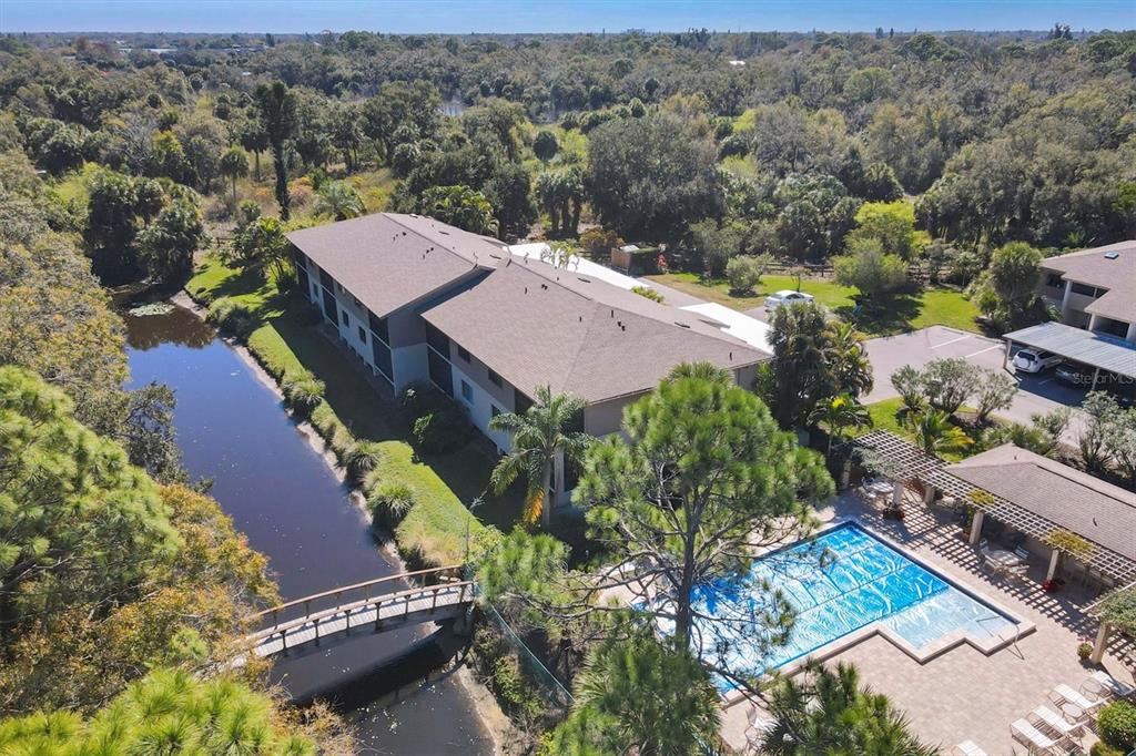 An aerial view of an apartment building with a swimming pool and a wooden bridge — 3363 CROSS CREEK DRIVE UNIT 3363, SARASOTA, FL