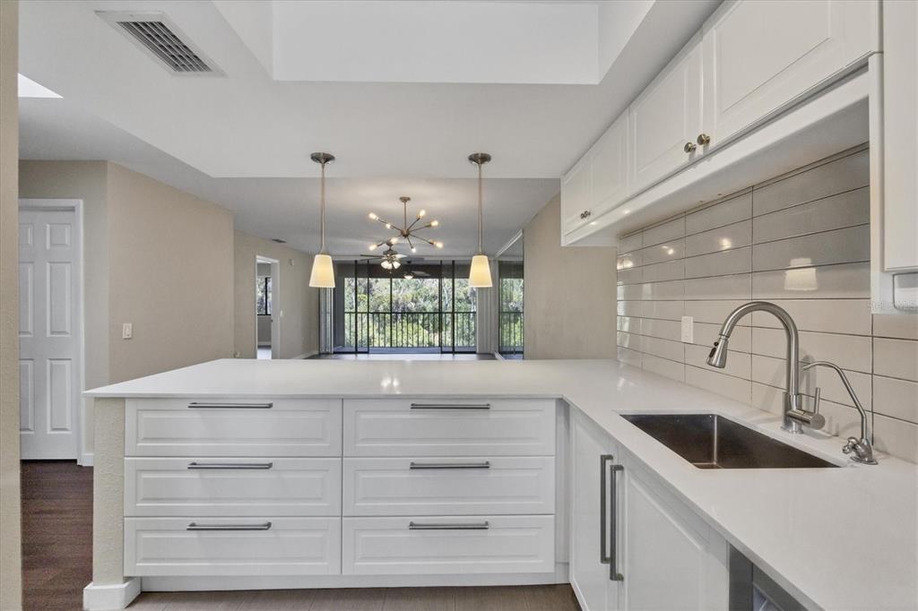 A white kitchen with a quartz island, subway tile backsplash, and views of a balcony — 3363 CROSS CREEK DRIVE UNIT 3363, SARASOTA, FL