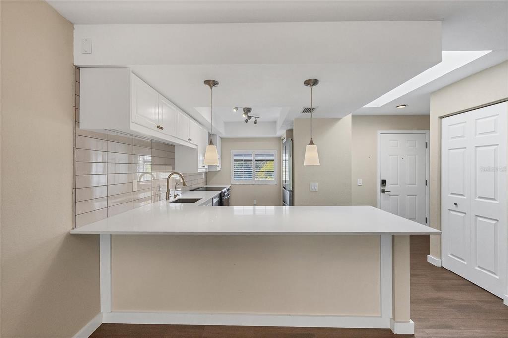 A kitchen features white cabinets, a quartz breakfast bar, and light-colored subway tile backsplash — 3363 CROSS CREEK DRIVE UNIT 3363, SARASOTA, FL