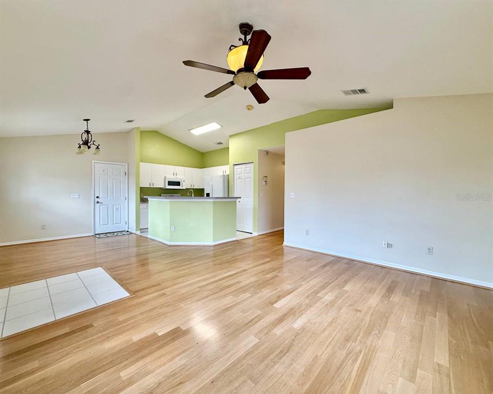 An open-concept living room features hardwood floors, a vaulted ceiling, and a kitchen with light-green walls — 6807 KINGSTON DRIVE, TAMPA, FL