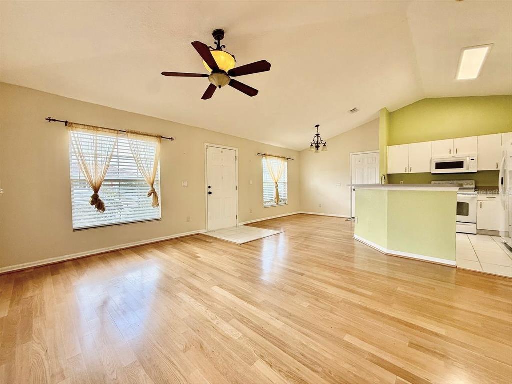 An open-concept living room and kitchen with light wood flooring and vaulted ceilings — 6807 KINGSTON DRIVE, TAMPA, FL