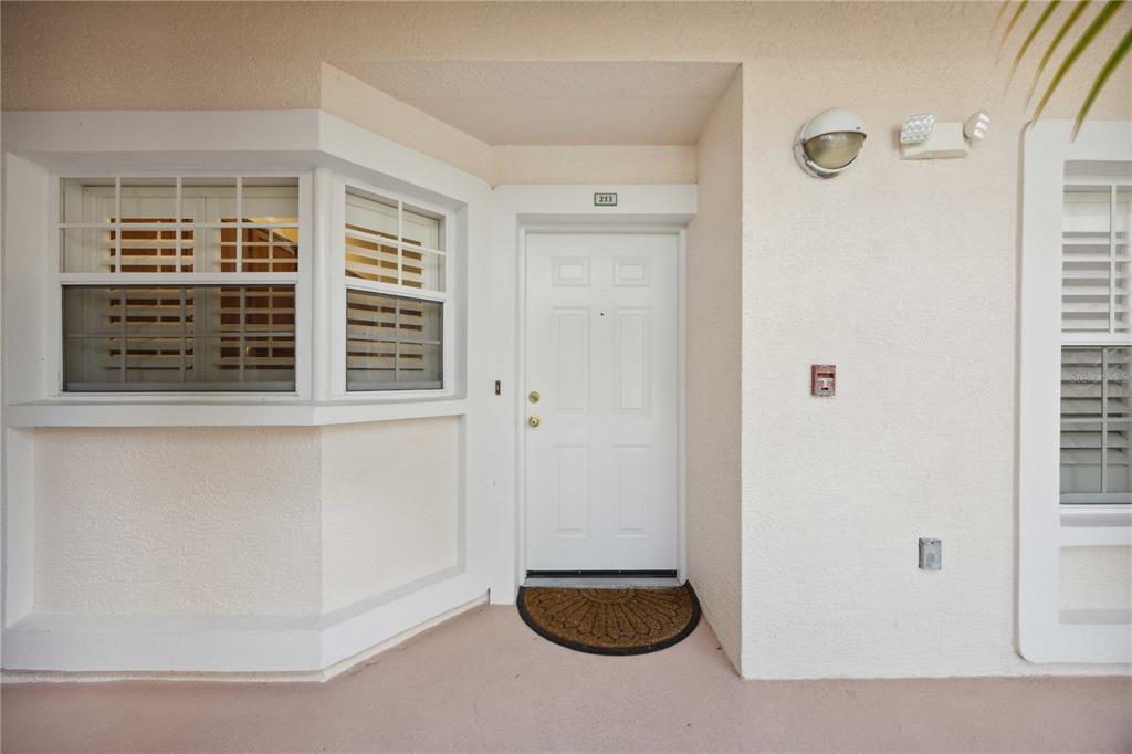A white front door with a bay window and a small welcome mat outside — 4260 CENTRAL SARASOTA PARKWAY UNIT 213, SARASOTA, FL