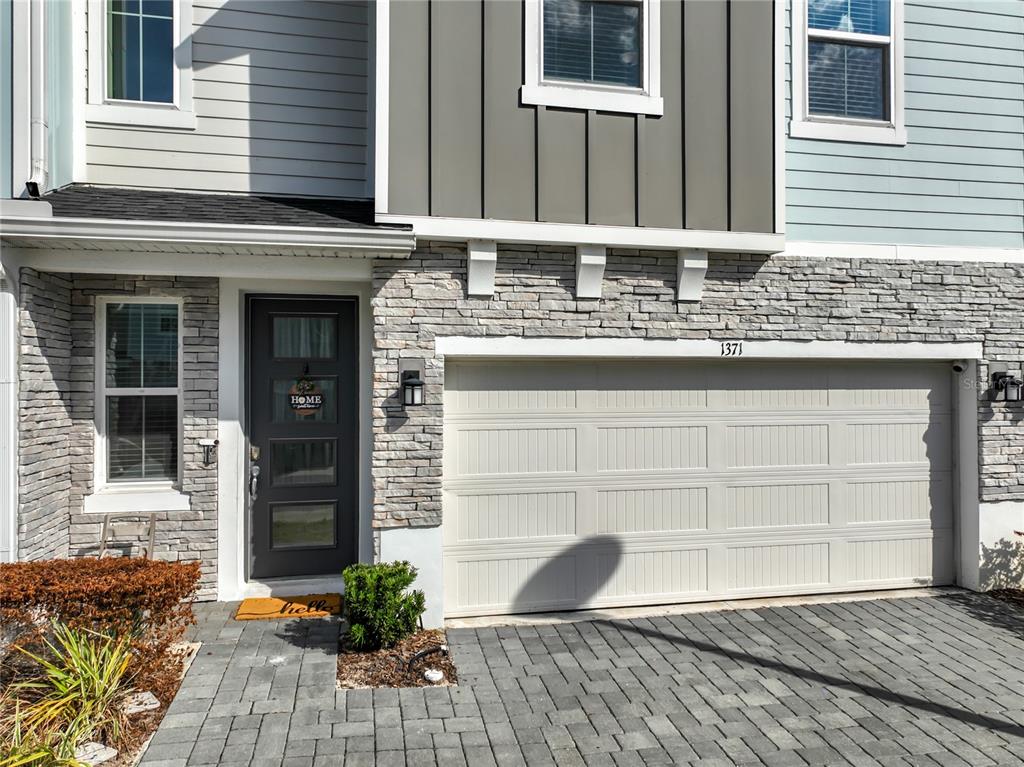 The exterior of a two-story townhouse features a stone facade, a garage, and a front door — 1371 CAPTIVA COVE, SANFORD, FL