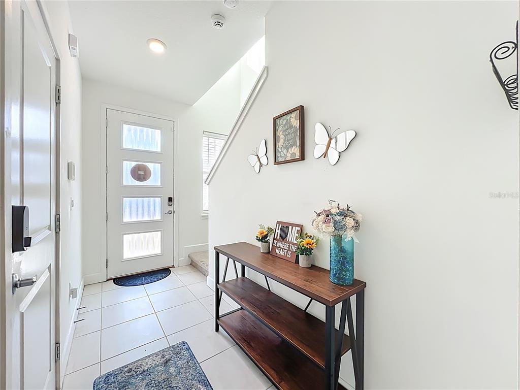 A bright entryway features white walls, tile flooring, a wooden console table, and a front door — 1371 CAPTIVA COVE, SANFORD, FL