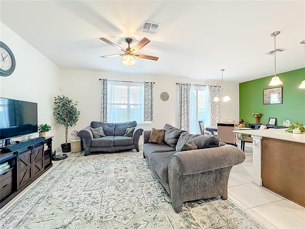 A living room features a grey sofa, a patterned rug, and an adjacent dining area — 1371 CAPTIVA COVE, SANFORD, FL
