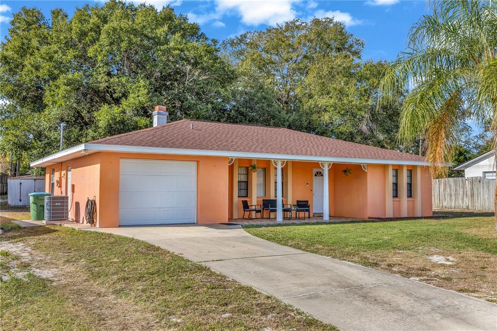 A single-story peach-colored house with a white garage door and a covered front porch — 1642 HORSESHOE TERRACE, DELTONA, FL