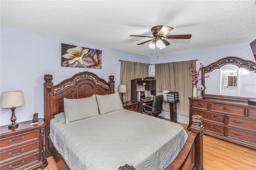 A bedroom features a wooden bed frame, matching dresser with mirror, and a small desk area — 1642 HORSESHOE TERRACE, DELTONA, FL