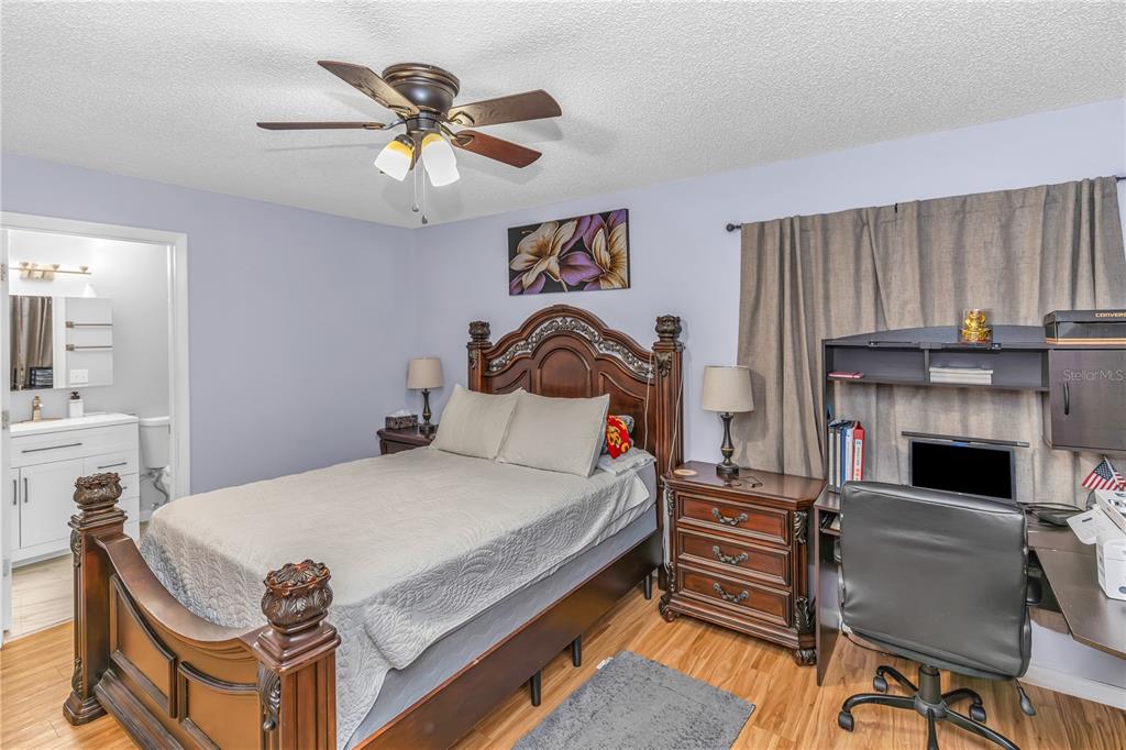 A bedroom features a wooden bed frame, a desk, a ceiling fan, and an attached bathroom — 1642 HORSESHOE TERRACE, DELTONA, FL