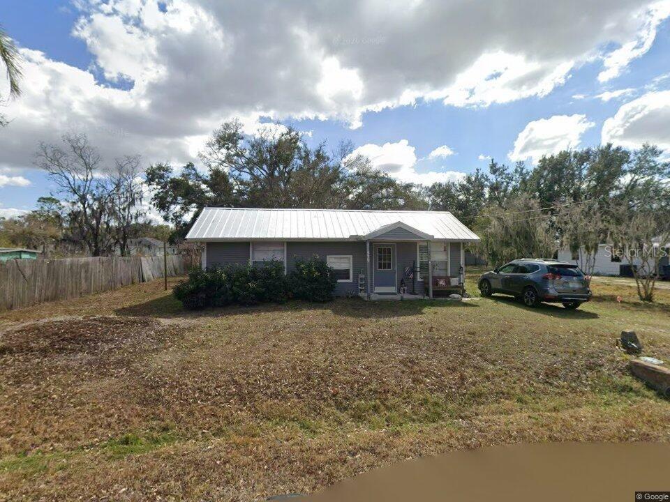 A single-story house with a metal roof and gray siding sits on a grassy lot — 11829 71ST STREET E, PARRISH, FL