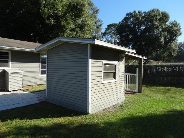 A gray vinyl-sided shed stands in a grassy backyard next to a residential house — 11829 71ST STREET E, PARRISH, FL
