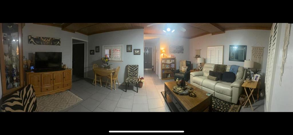 A panoramic view of a living room and dining area with tile flooring and wood ceilings — 11829 71ST STREET E, PARRISH, FL