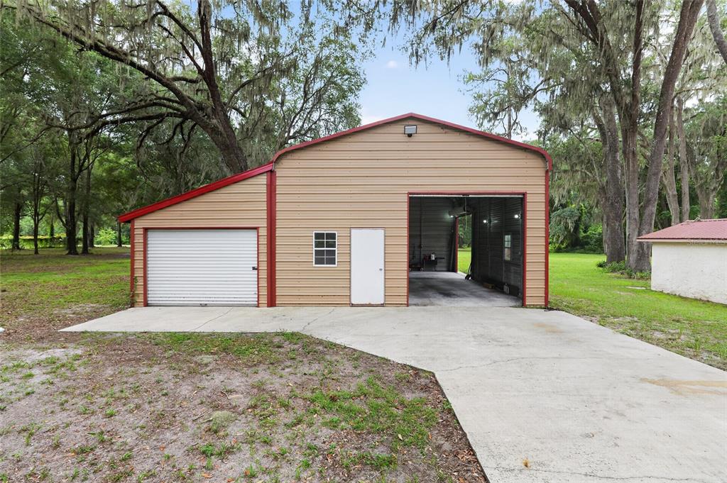 A metal workshop building with a roll-up door, a side door, and a concrete driveway — 18741 N US HIGHWAY 301, CITRA, FL