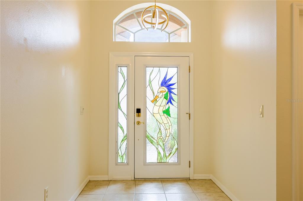 An entryway features a white door with a seahorse stained-glass insert and a transom window — 18014 JAVA ISLE DRIVE, TAMPA, FL