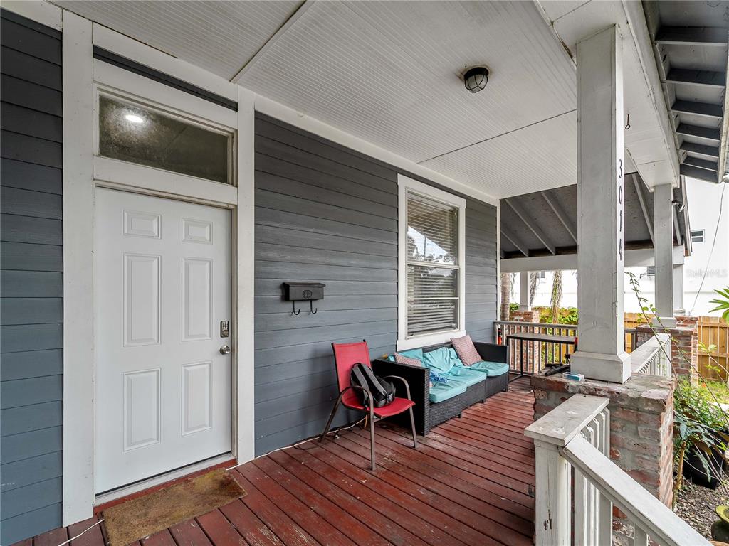 A covered front porch features dark gray siding, a white door, and a wooden deck — 3014 N TAMPA STREET, TAMPA, FL