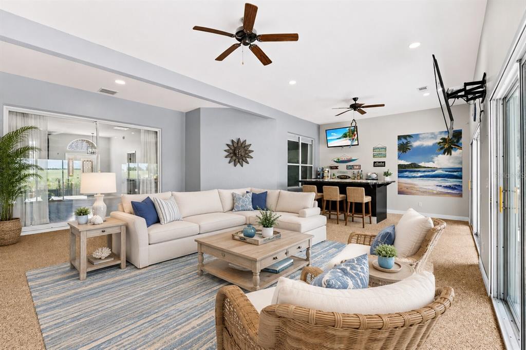 A living room features a sectional sofa, a bar area, and wicker chairs on carpet — 25501 MAUREPAS LANE, LEESBURG, FL