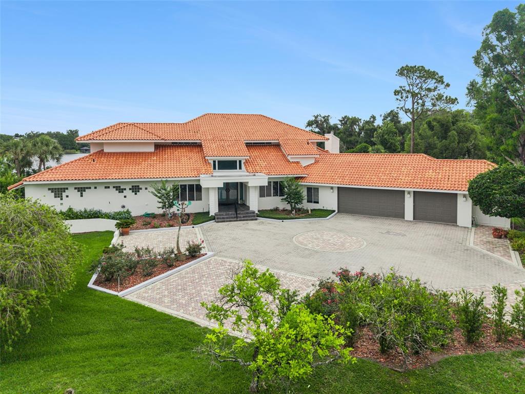 An aerial view of a large house with a terracotta tile roof and paved driveway — 315 MENASHE COURT, LONGWOOD, FL