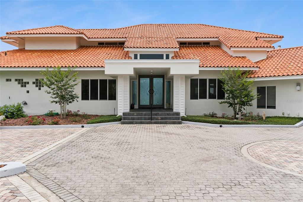 The exterior of a house features a terracotta tile roof, white stucco walls, and a driveway — 315 MENASHE COURT, LONGWOOD, FL