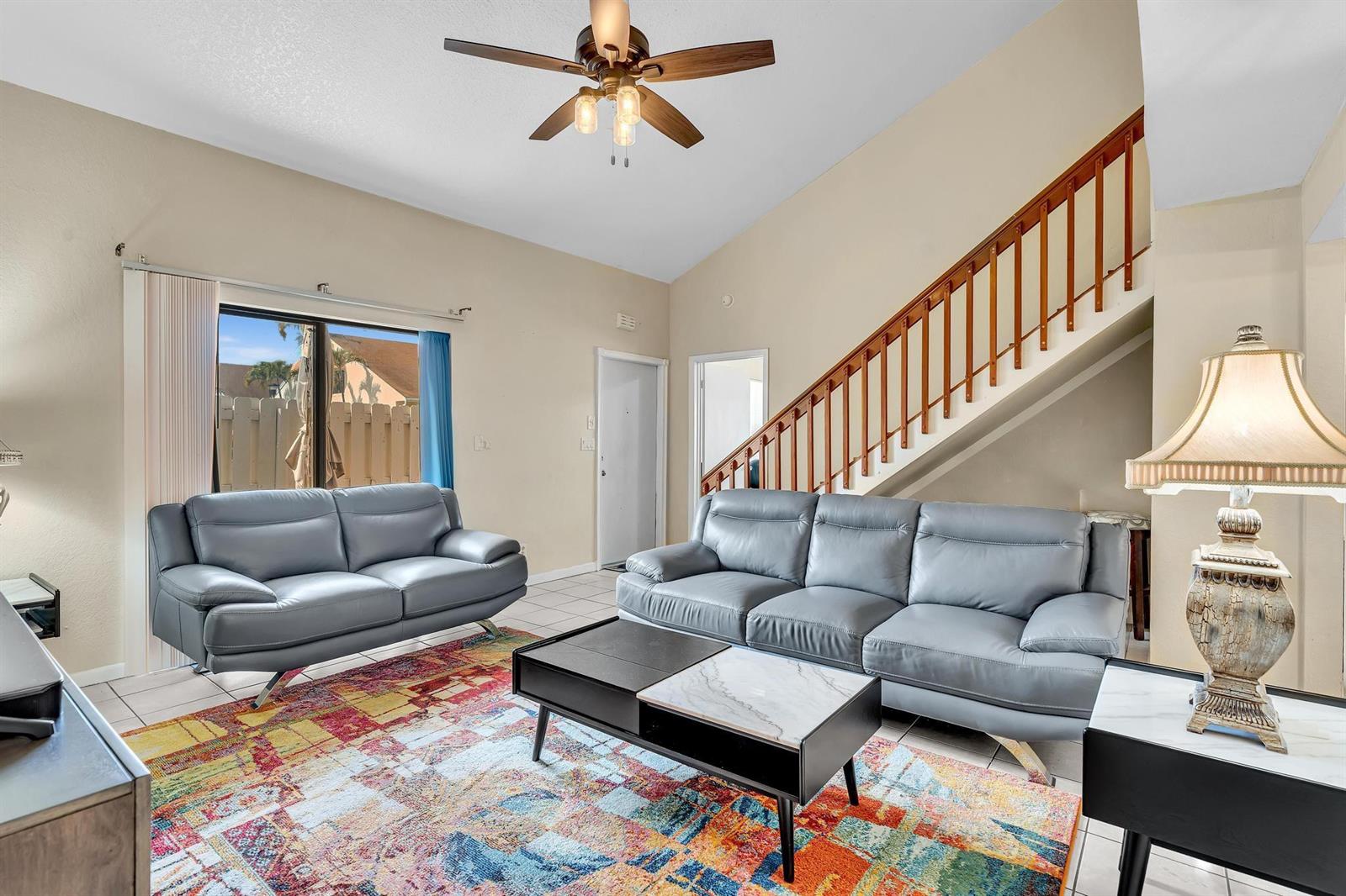 A living room with vaulted ceilings, gray leather sofas, a colorful rug, and tile flooring — 10240 NW 33rd Place, Sunrise FL 33351, SUNRISE, FL