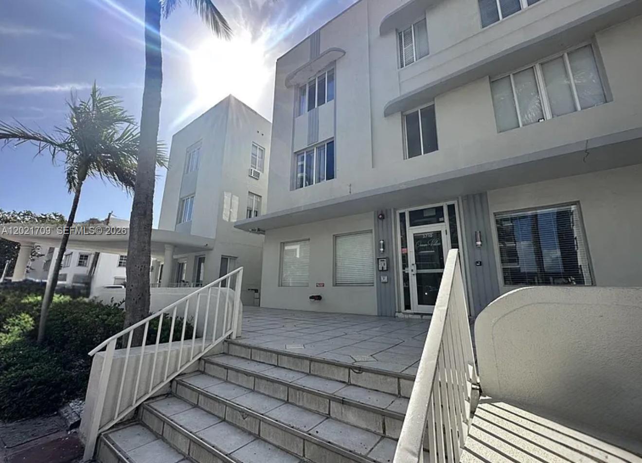 A low-angle exterior view shows a multi-story building with white stairs leading to the entrance — 3700 Collins Ave # 306, Miami Beach FL 33140, MIAMI BEACH, FL