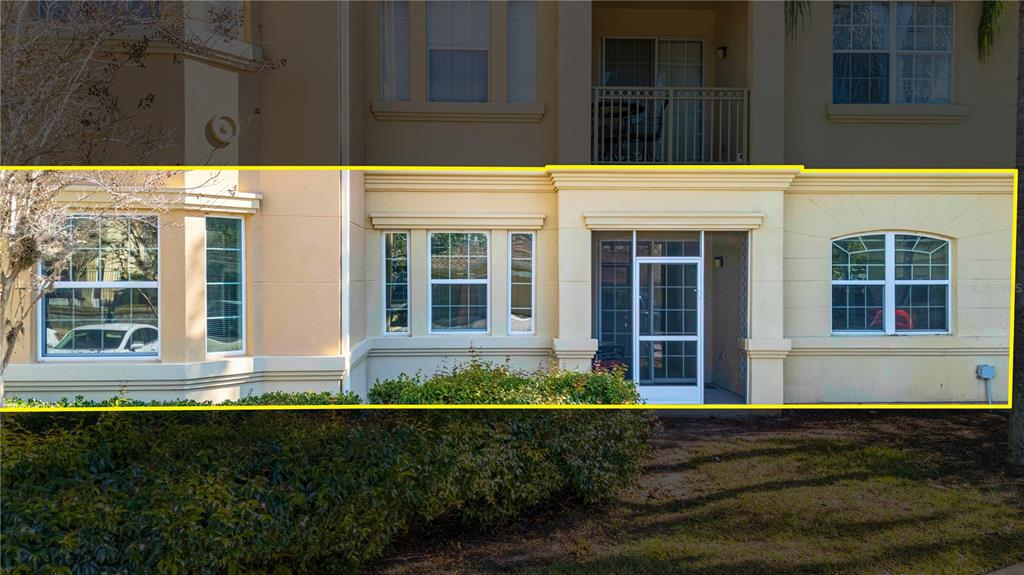 The exterior of a ground-floor condo unit features a screened patio and multiple windows — 707 TERRACE RIDGE CIRCLE UNIT 707, DAVENPORT, FL