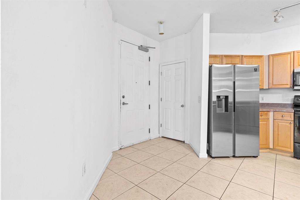 A tiled entryway features a white front door, a closet door, and a stainless refrigerator — 707 TERRACE RIDGE CIRCLE UNIT 707, DAVENPORT, FL