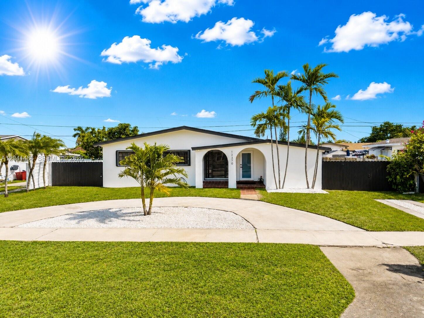 A single-story white house with a curved entryway and palm trees sits behind a lawn — 12370 SW 190th Ter, Miami FL 33177, MIAMI, FL