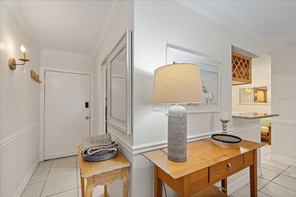 An entryway features a white door, two wooden console tables, and a wall-mounted light fixture — 3360 S OSPREY AVENUE UNIT 104B, SARASOTA, FL
