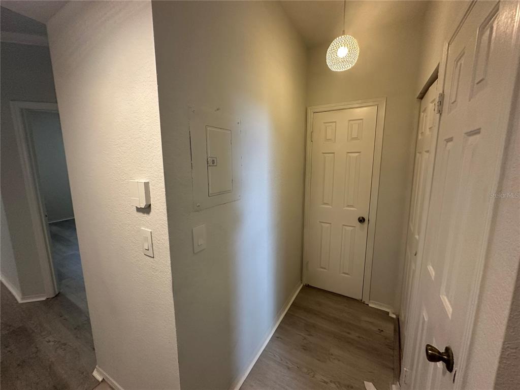 A hallway features light wood-look flooring, a white door, a closet, and a ceiling light — 2598 ROBERT TRENT JONES DRIVE UNIT 1027, ORLANDO, FL