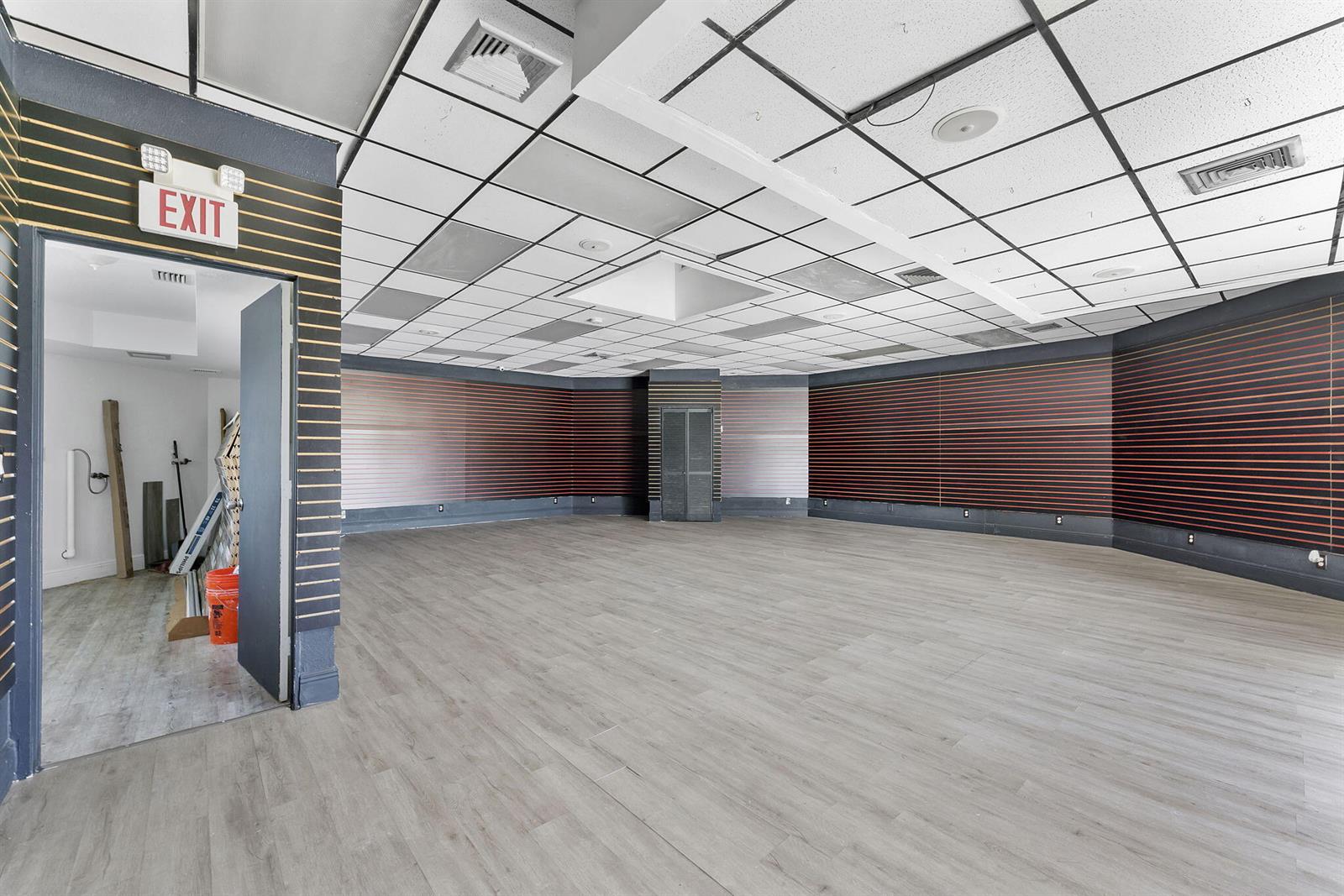 An empty commercial space features wood-look flooring, slat-wall paneling, and a drop ceiling — 888 E Coast Avenue, Lantana FL 33462, LANTANA, FL