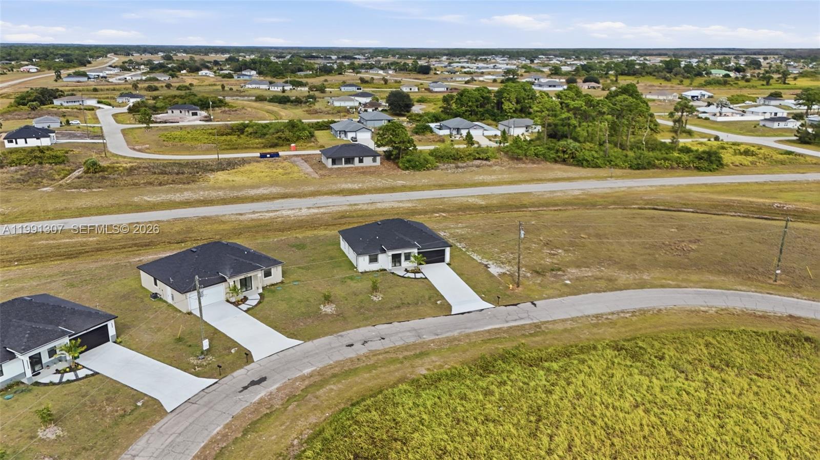 An aerial view shows several modern single-family homes situated in a rural, undeveloped landscape — 9027 bamboo cir, La Belle FL 33935, LA BELLE, FL